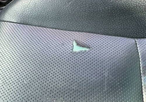 Close-up of a torn black leather car seat with a hole – Leather Seat Restoration in San Diego