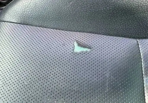 Close-up of a torn black leather car seat with a hole – Leather Seat Restoration in San Diego