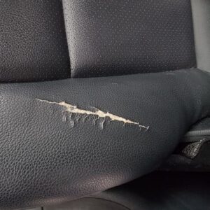 Torn black leather car seat before repair