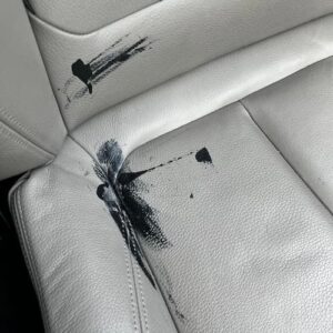 Leather car seat with black paint stains before restoration
