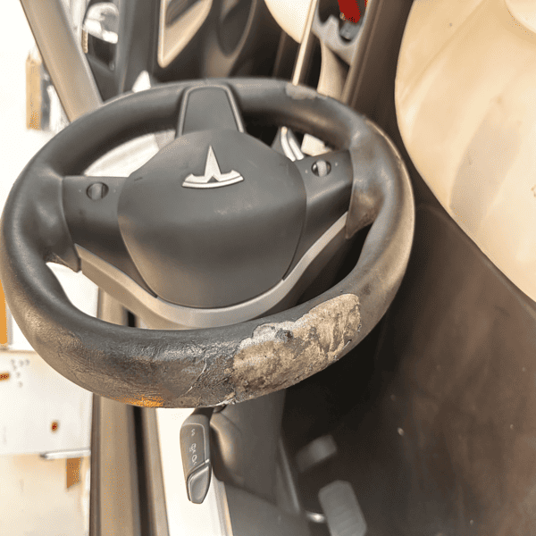 Tesla steering wheel before restoration – peeling polyurethane coating