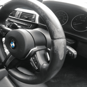Worn BMW leather steering wheel with faded and damaged surface before professional steering wheel repair in san diego.