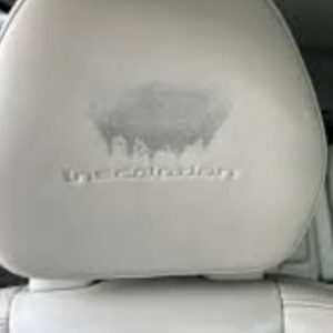 White leather car seat headrest with a large faded patch requiring coloring leather car seats restoration