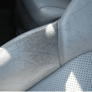 Faded grey leather car seat with worn color caused by aging and repeated cleaning