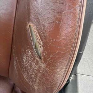 Damaged leather seat bolster with deep cracks and tear