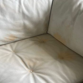 Close-up of leather couch before restoration, showing orange stains and paint loss — a typical leather couch restoration case